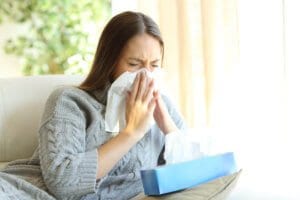woman sneezing before removing allergens in the home