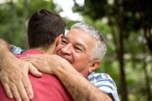 Adult son hugging his senior dad